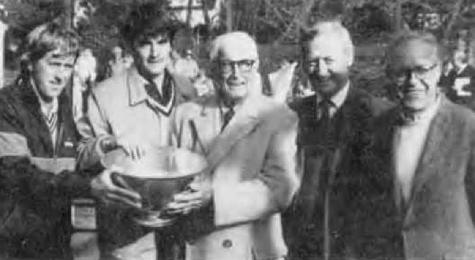 Killy Kilmarx (center), the winner of the first Men's Championship with Clifford Couch in 1935, presents the Championship bowl to the fifty-second championship pair of Hank Irvine (left) and Greg Moore. Dick Warren (right), FMTC president, and Paul Molloy, tournament chairman.