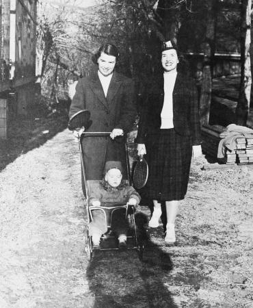 "Wheeling son, Edward, Jr., who will join spectator ranks, is Mrs. Edward S. Cooke of South Orange, as she arrives with Mrs. Ned Williams, Orange, at courts to join waiting husbands"