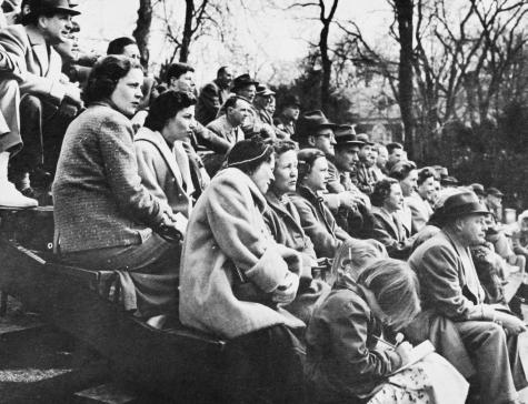The spectator gallery at Fox Meadow Tennis Club, Scarsdale, NY. All but one intent on the match