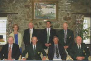 Board of Trustees to the Foundation: Standing (L) to (R) - Alice Duff, Charles Updike, Howard Patterson, David Childs: Seated (L) to (R) Joseph Rogers, Treasurer, Robert Brown, Chairman, Richard Lombard, President and Charles Vasoll, Secretary. Photo taken at the Fox Meadow Tennis Club with the original painting of play on Court One and the clubhouse in the background.